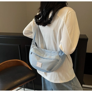 Détail du sac à bandoulière demi-lune bleu clair avec étiquette de marque sur le modèle