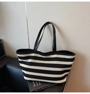 Detail of the thick knitted texture and black leather handles on this striped tote bag