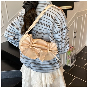 Dettaglio della borsa sottobraccio beige plissettata stile balletto con fiocchi