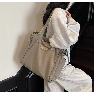 Dettaglio della borsa tote kaki con coulisse laterale e logo in pelle in ambiente lifestyle
