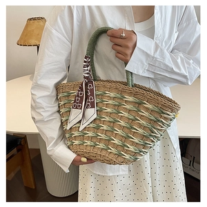 Close-up of woven straw handbag featuring green mixed texture and decorative bear scarf