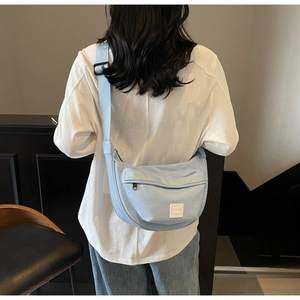 Vue arrière d'un mannequin portant un sac besace en toile bleu clair avec bandoulière