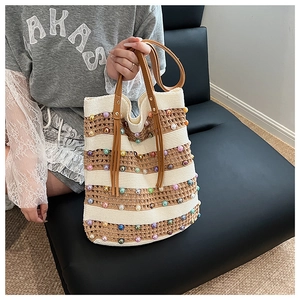 Détail d'un sac cabas tissé à rayures avec perles colorées et pompon en cuir
