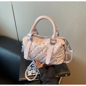 Detailed view of pink quilted leather handbag featuring crystal diamond studs on surface