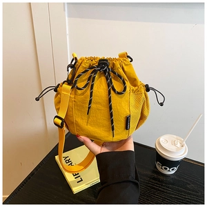 Detail of yellow nylon bucket bag with drawstring closure and black toggle cord