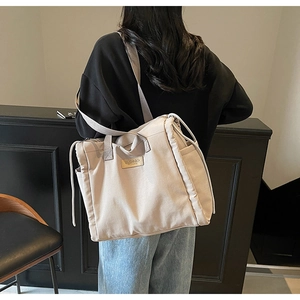 Dettaglio della tasca laterale con coulisse e logo in pelle su questa borsa tote beige