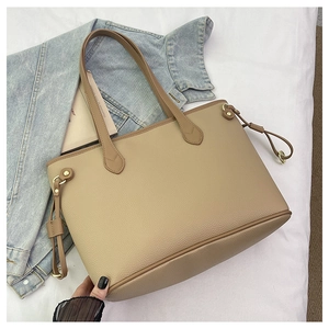 Detail of lychee textured leather tote bag with side drawstrings and gold hardware