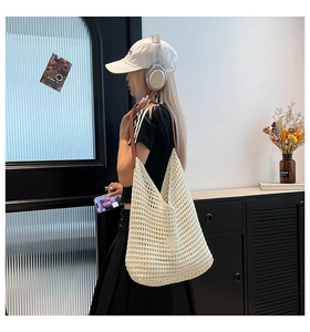 Detailed shot of a white hollow crochet tote bag with brown leather handles and metal hardware