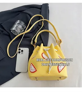 Detail view of yellow drawstring bucket bag with fruit patches and bottom metal rivets