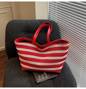 Close-up of red and white striped knit tote bag showing woven texture and leather handles