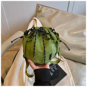 Detail of green nylon drawstring bucket bag with mesh side pocket and crossbody strap