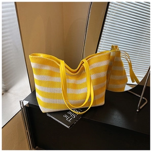 Détail du sac cabas tissé à rayures jaunes et blanches avec lanières en cuir sur présentoir