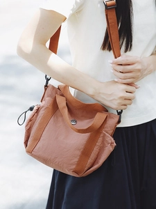 Minimalist brown nylon crossbody bag with adjustable strap and round metal logo
