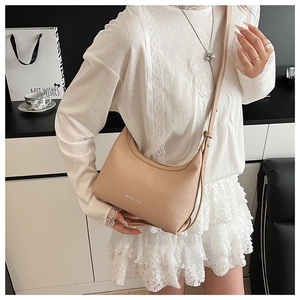 Detail of beige pebble leather dumpling bag with metal logo and adjustable strap