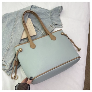 Detail of light blue lychee pattern tote bag with brown straps and golden ring hardware