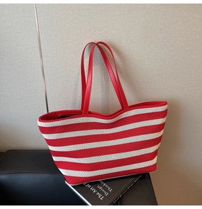Detailed shot of red and white striped woven tote bag with smooth leather handles