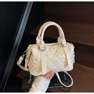 Close-up of quilted ivory handbag featuring sparkling rhinestones and silver hardware