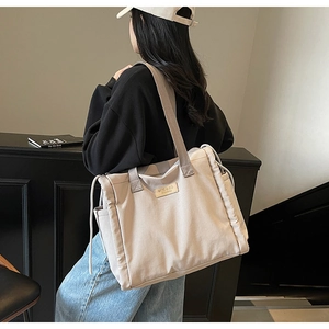Foto lifestyle di una capiente borsa tote in tela bianco avorio con logo in pelle e coulisse