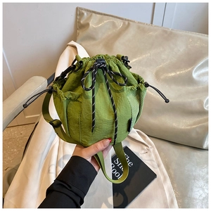 Detail of green nylon bucket bag with drawstring closure and side mesh pocket