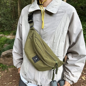 Detail view of olive green wrinkled nylon crossbody bag with buckle strap on model