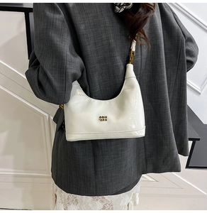 Dettaglio di una borsa a mezzaluna bianca in pelle lucida con logo metallico COIN