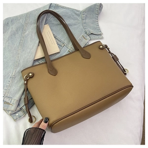 Detail of khaki lychee grain leather tote bag with dark brown edges and gold hardware