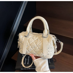 Detail of beige quilted bucket bag with rhinestone accents and round top handles