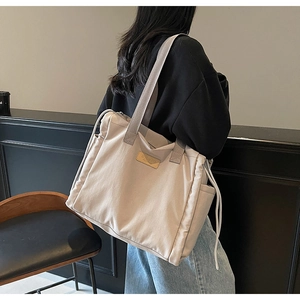 Grande borsa tote in nylon beige indossata dal modello per il pendolarismo quotidiano