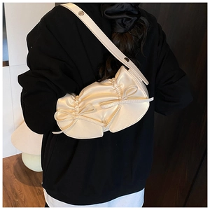 Dettaglio borsa a mezzaluna color crema stile balletto con morbide pieghe e fiocchi decorativi