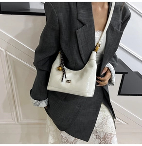 Dettaglio della borsa a mezzaluna in pelle cerata bianca con logo dorato e charm