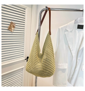 Close-up of light green hollow-out woven hobo bag with brown leather shoulder strap