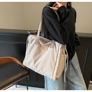 Vista dettagliata della grande borsa tote in tela con patch logo e lati a coulisse
