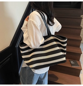 Detail of a large black and white striped woven tote bag with leather straps for daily use