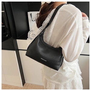 Detail of black lychee grain leather crescent bag featuring white letter logo on the side