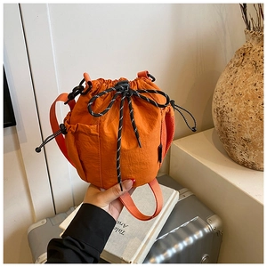 Detail of bright orange nylon drawstring bucket bag with sporty mesh and woven strap