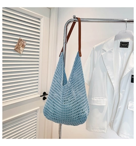Detail of blue crochet tote bag showing hollow knit texture and brown leather handle