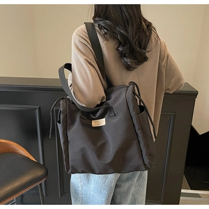 Dettaglio della borsa tote in tela nera con tracolla larga e coulisse laterale regolabile