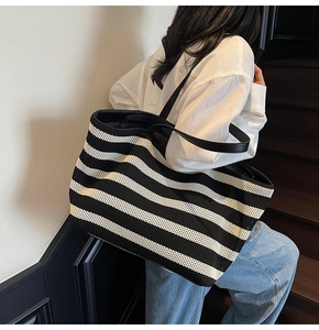 Detail of black and white striped woven tote bag with a fine mesh texture and slim straps