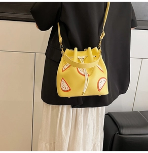 Detail view of yellow bucket bag with watermelon print worn by a model on shoulder