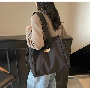 Dettaglio della grande borsa tote nera con patch logo e texture in nylon resistente