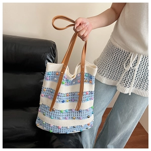 Détail du sac cabas en tricot à rayures bleues et blanches avec perles et poignée en cuir