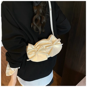 Dettaglio della borsa a tracolla plissettata color bianco latte con fiocchi eleganti
