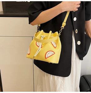 Close-up of a yellow bucket bag with orange fruit slices and drawstring detail
