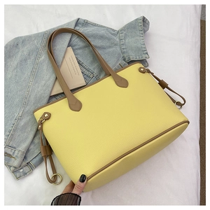 Detail of yellow pebbled leather tote bag with brown straps and gold metal hardware