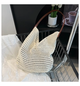 Macro detail of white hollow crochet tote bag with brown faux leather straps in a metal basket