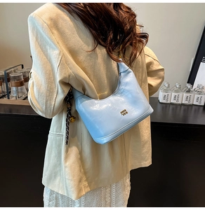 Dettaglio della borsa hobo in pelle lucida azzurra con logo oro e ciondolo a campanello