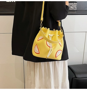 Detail view of yellow drawstring bucket bag with watermelon embroidery worn by a model