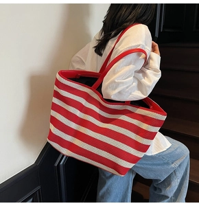 Detail showing red and white striped knit texture and red leather handles on a tote bag