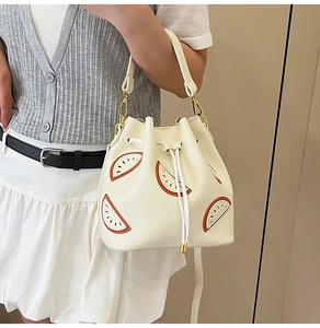 Detail of off-white drawstring bucket bag with cute watermelon embroidery and gold buckles