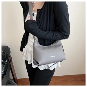 Detail of grey lychee leather texture and silver hardware on a crescent shoulder bag